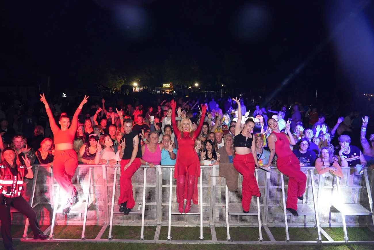 The Kylie Minogue tribute show and dancers in red posing in front of a packed festival crowd at night