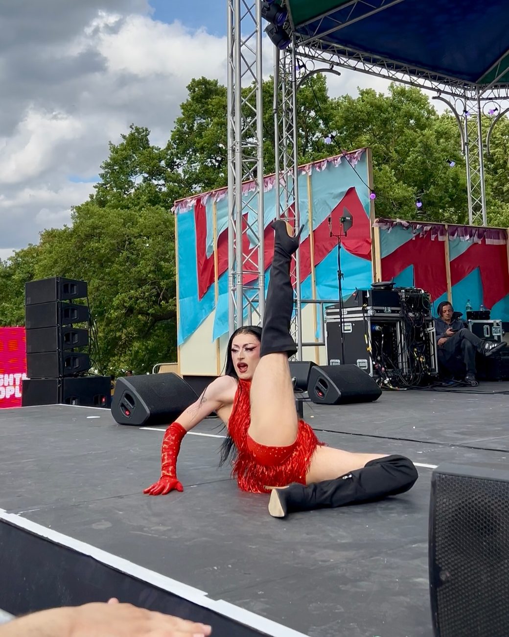 Charlie Sin in red, mid floor-work on a large outdoor festival stage